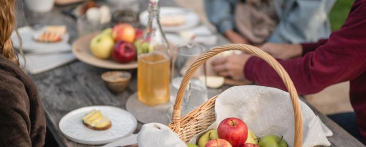 A basket full of apples on a picnic table